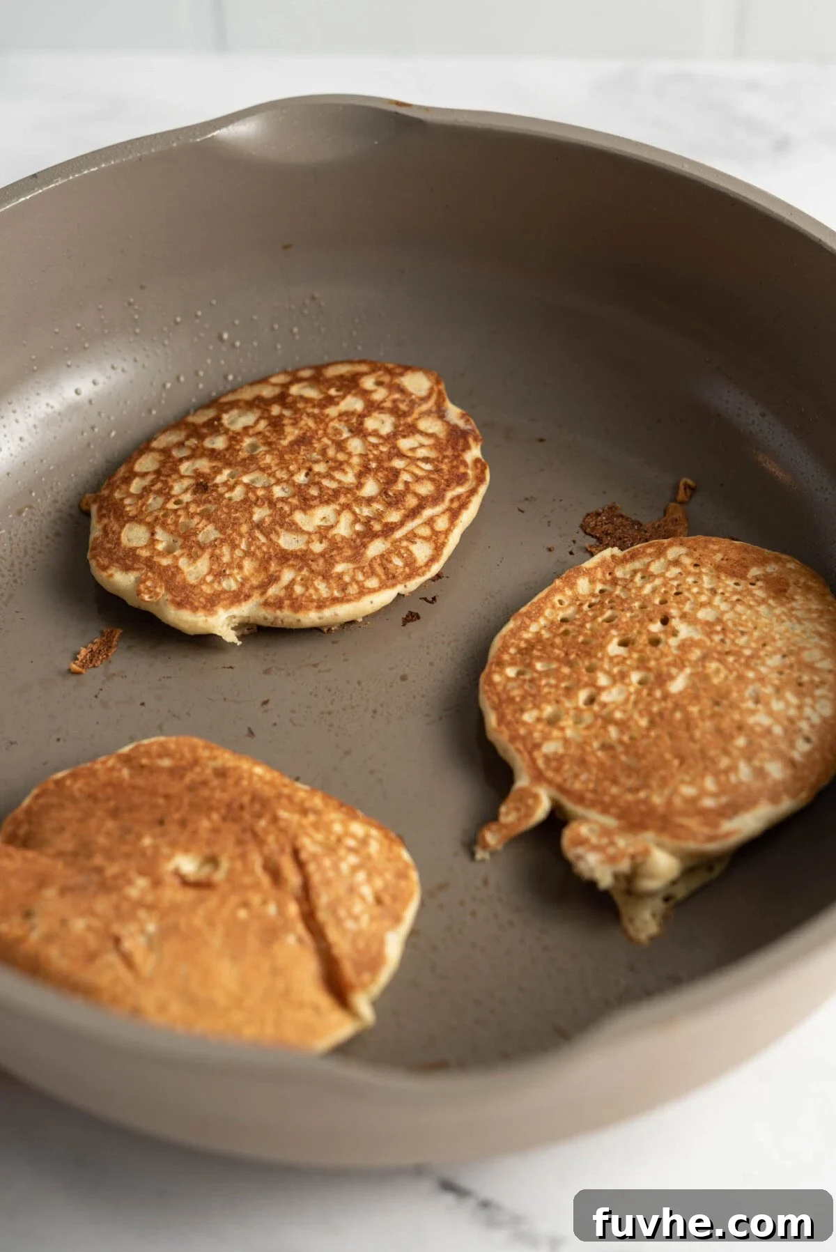 Protein-Packed Vegan Quinoa Pancakes 7 3 quinoa flour pancakes cooking in a skillet.