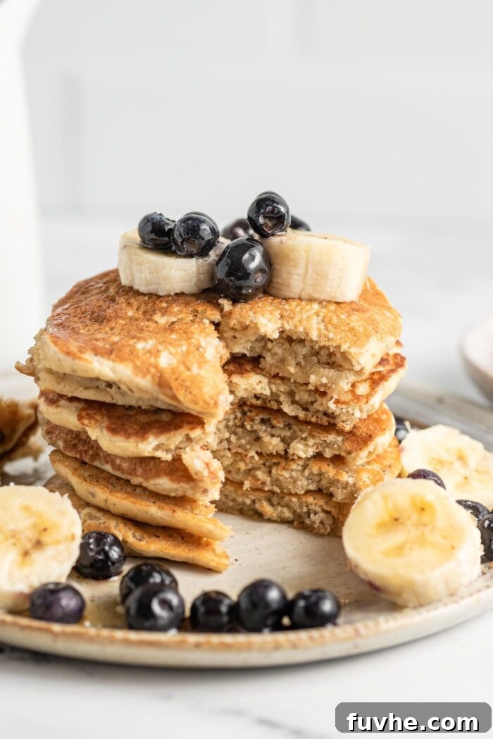Protein-Packed Vegan Quinoa Pancakes 10 Close up of a stack of pancakes that have been sliced to show the texture inside. The pancakes are topped with blueberries and banana.