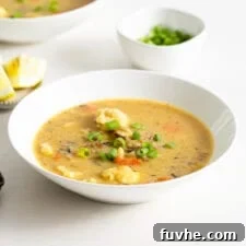 Bowl of vegan cauliflower wild rice soup topped with sliced green onion.