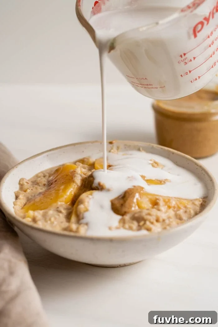 Velvety Vegan Peach Dream Bowl 5 A measuring cup pouring milk into a bowl of peach oatmeal.
