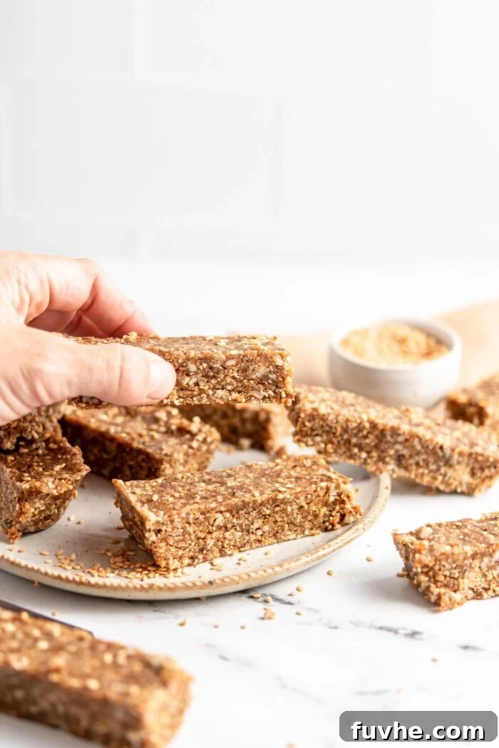 A hand reaching for an energy bar from a plate full of homemade bars.