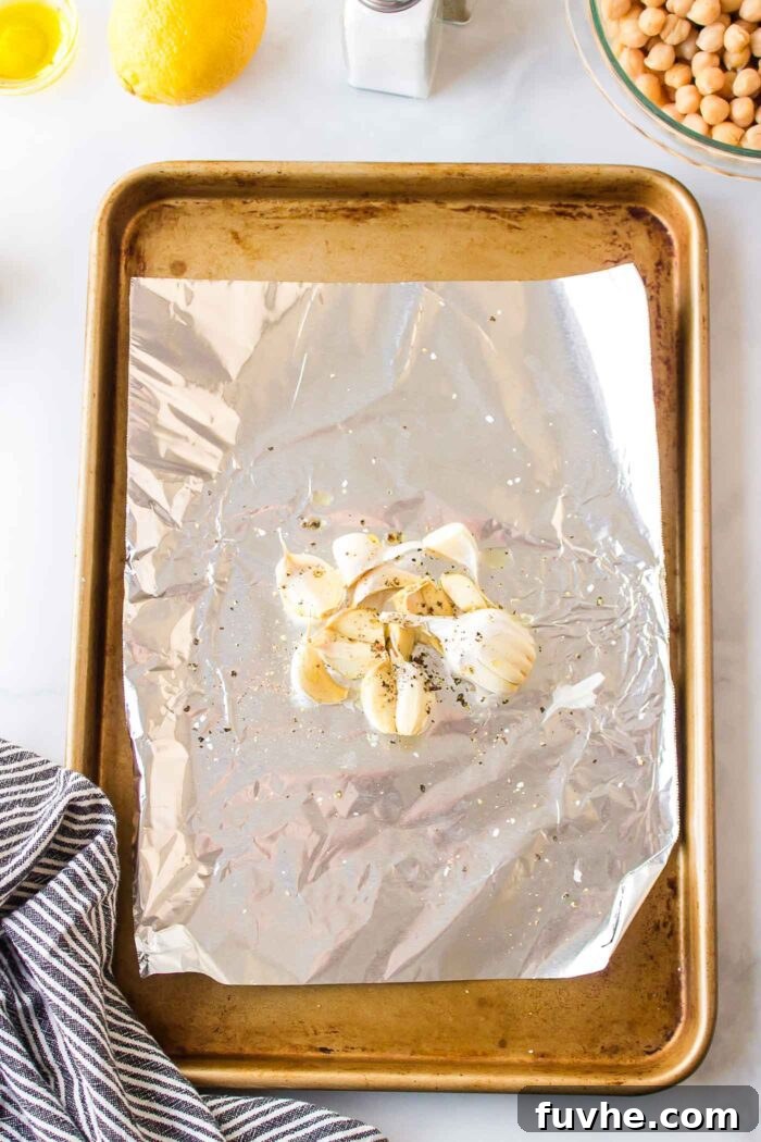 Whole cloves of garlic on a piece of foil on a roasting tray.