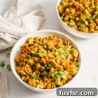 Two bowls of vegan fried brown rice sitting on a white surface.