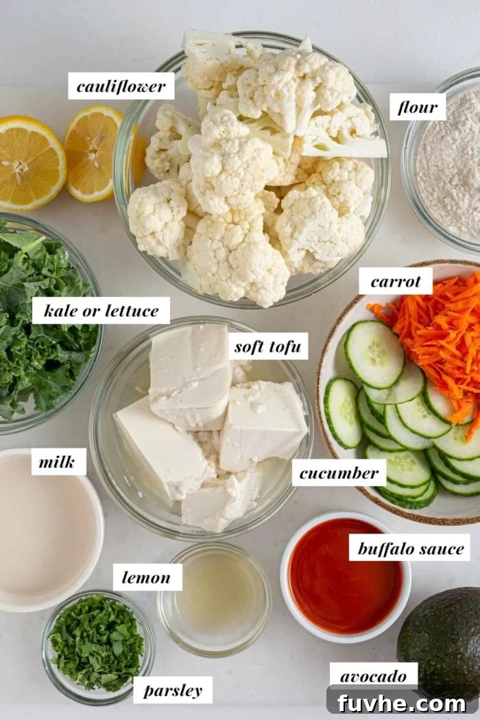 Tangy Buffalo Cauliflower Wraps 3 Labelled ingredients for making a buffalo cauliflower wrap with avocado, kale, cucumber and carrot laid out on a clean surface.