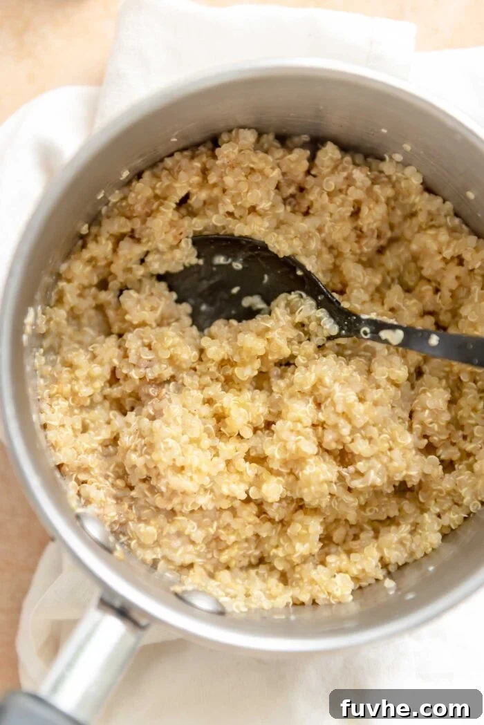 Cooked quinoa gently heating in a small saucepan, with a spoon resting, illustrating the quick 5-minute breakfast method.