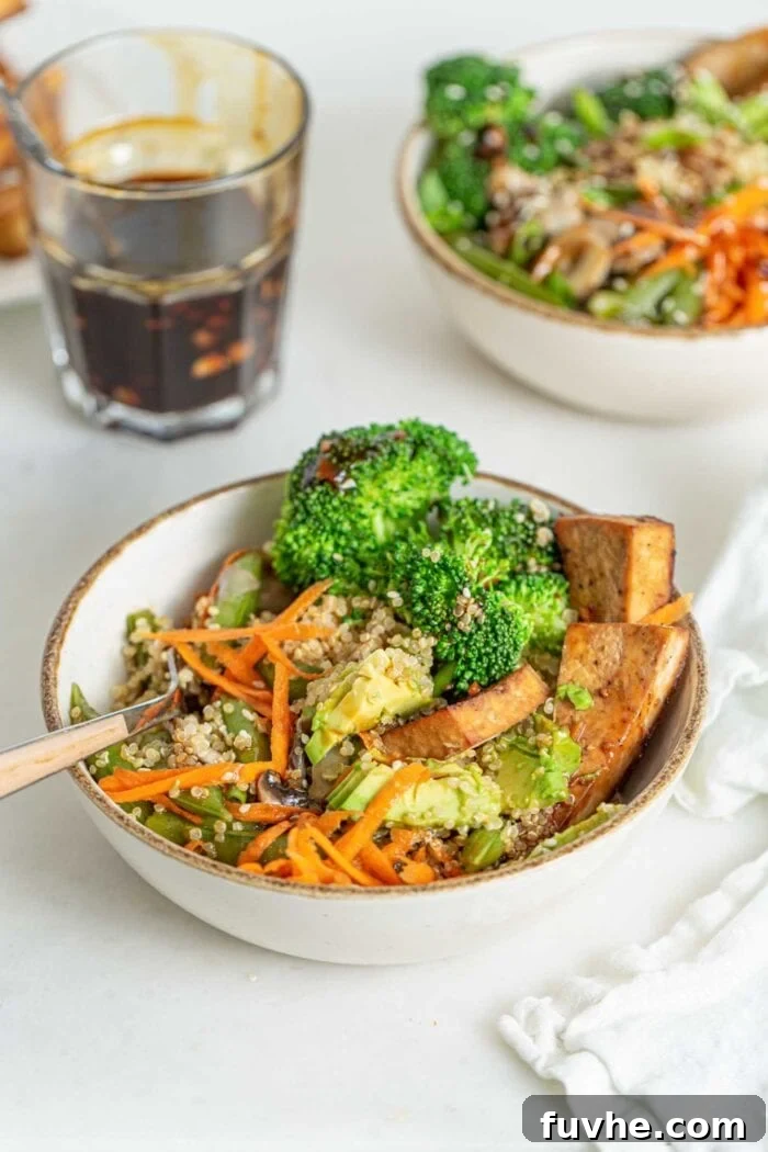 A close-up shot of quinoa, grated carrot, steamed broccoli, and baked tofu, perfectly mixed together in a bowl with a fork, highlighting the inviting textures of the ingredients.