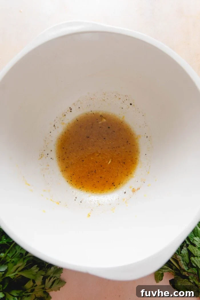 Freshly whisked lemon vinaigrette in a large mixing bowl, ready for the freekeh salad.
