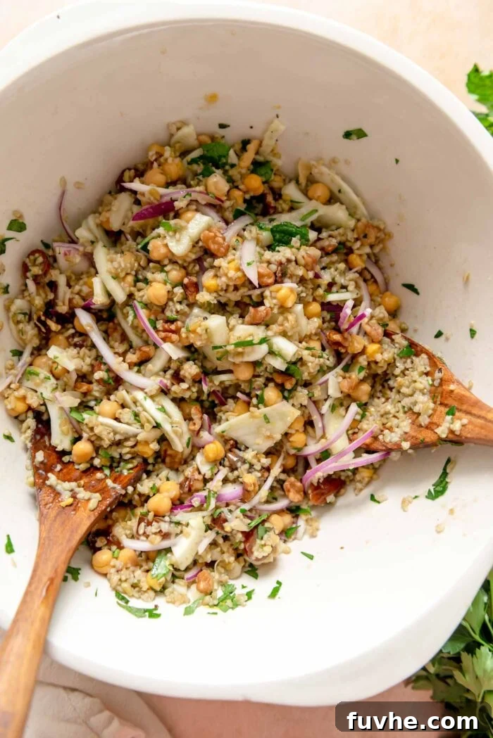 A vibrant Freekeh Salad in a large bowl, showcasing cooked freekeh, crisp fennel, tender chickpeas, sweet dates, and thinly sliced red onion, all tossed in a dressing.