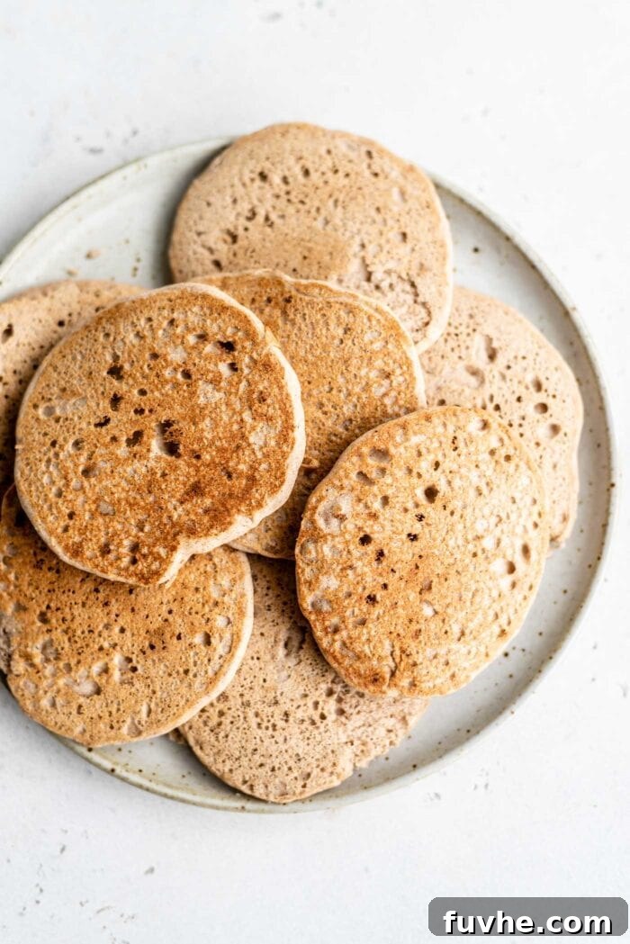 Plant-Based Buckwheat Power Pancakes 6 A generously piled plate full of freshly cooked, golden-brown buckwheat pancakes, ready to be adorned with toppings and enjoyed as a satisfying breakfast.