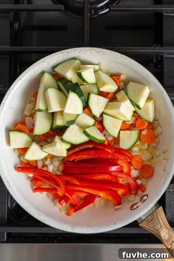 Creamy Vegan Panang Tofu Curry 5 Diced zucchini and thinly sliced bell pepper in a skillet with carrot, onion and garlic, after spices have been added and stirred.
