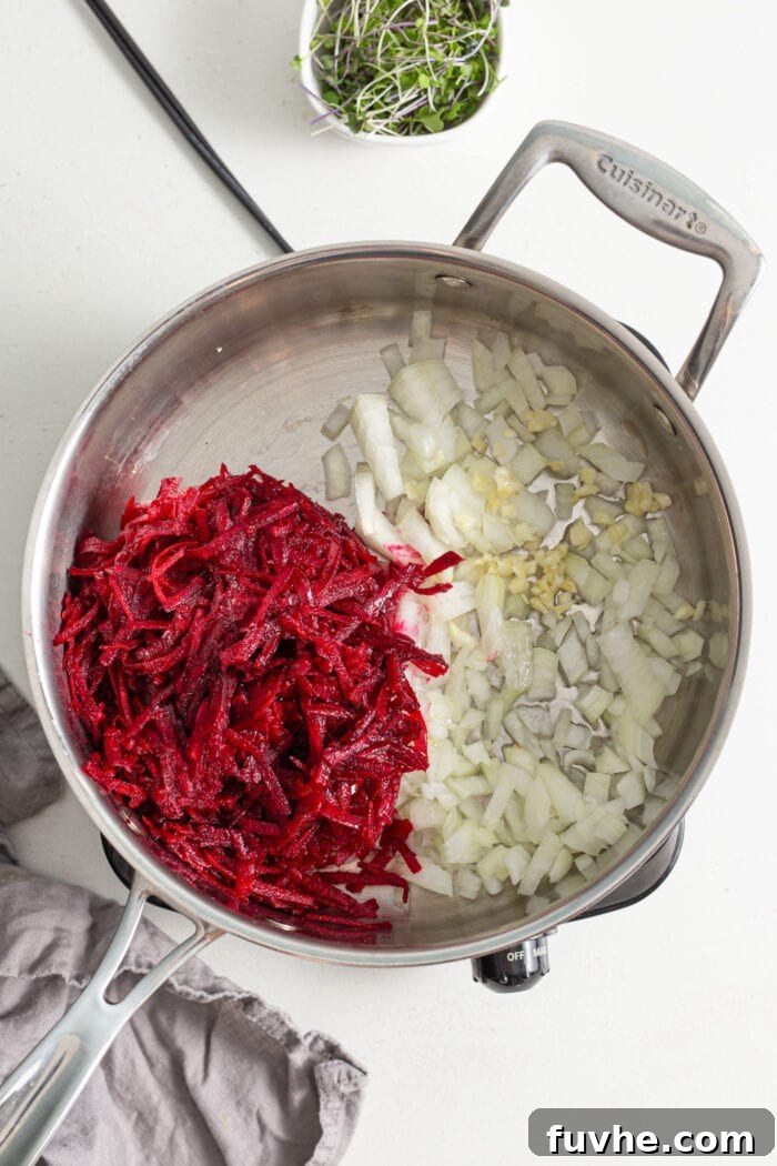 A colorful blend of freshly grated beet, finely diced onion, and minced garlic gently cooking in a non-stick skillet on the stovetop, releasing their fragrant aromas.