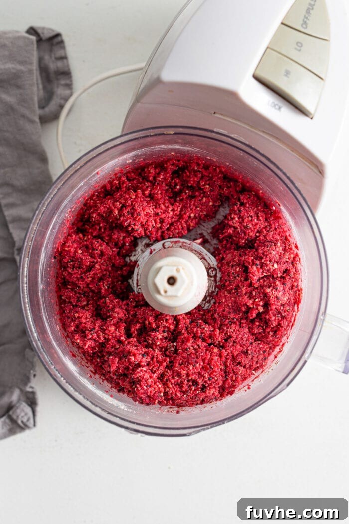The vibrant raw beet burger mixture inside a food processor bowl, a cohesive and colorful blend of all ingredients, prepared for shaping.