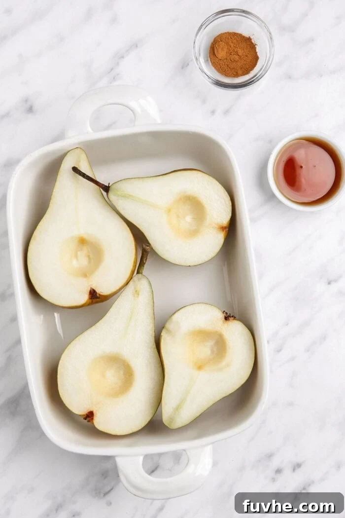 Warm Cinnamon Pear Delight 4 Precisely sliced open pears, with their seeds meticulously removed, neatly arranged in a sturdy baking dish, ready for seasoning.