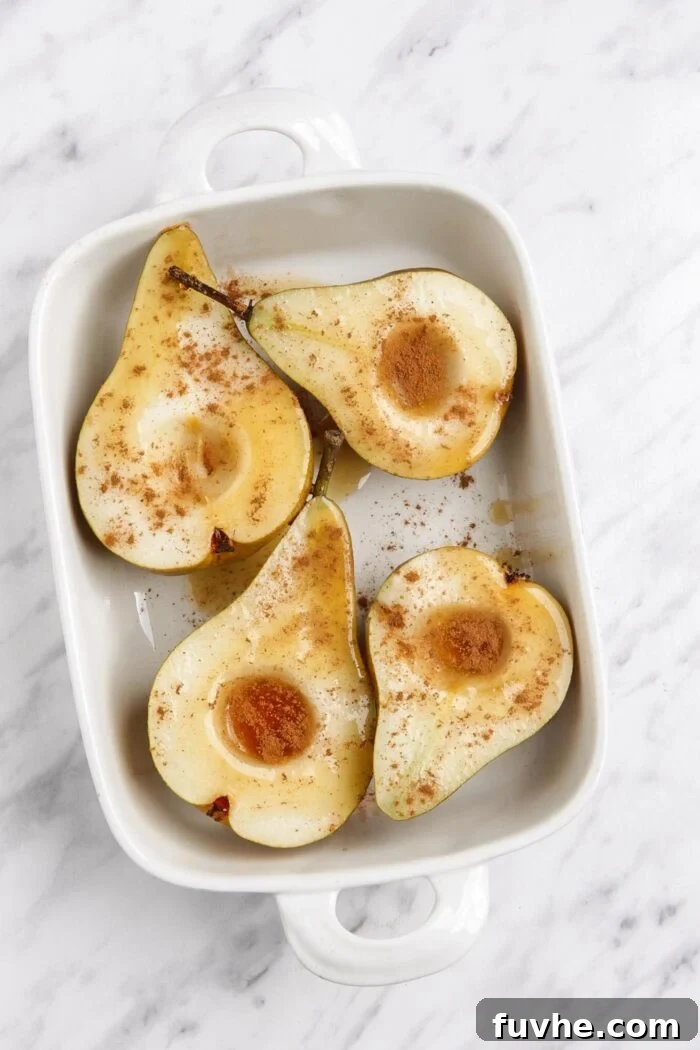 Warm Cinnamon Pear Delight 5 Expertly spiced open pears, beautifully arranged in a baking dish, glistening with maple syrup and aromatic cinnamon.