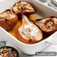 Four halves of baked pears topped with maple syrup and whipped cream in a baking dish.