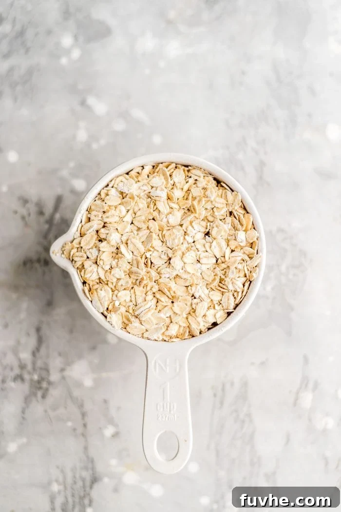 One cup of wholesome rolled oats in a white measuring cup, ready to be transformed into creamy oat milk.