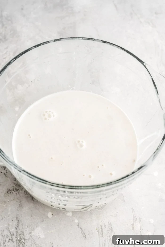 Creamy, healthy homemade oat milk proudly displayed in a clear glass measuring cup, showcasing its inviting texture.