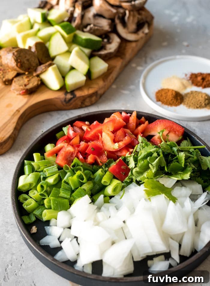 Plant-Powered Breakfast Skillet 3 A vibrant selection of fresh ingredients laid out, including sliced vegan sausage, various chopped vegetables, and spices, representing the components of a delicious vegan breakfast skillet.