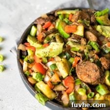 A beautifully presented plate of chopped veggies with creamy avocado and savory vegan sausage slices, ready for a delicious breakfast.