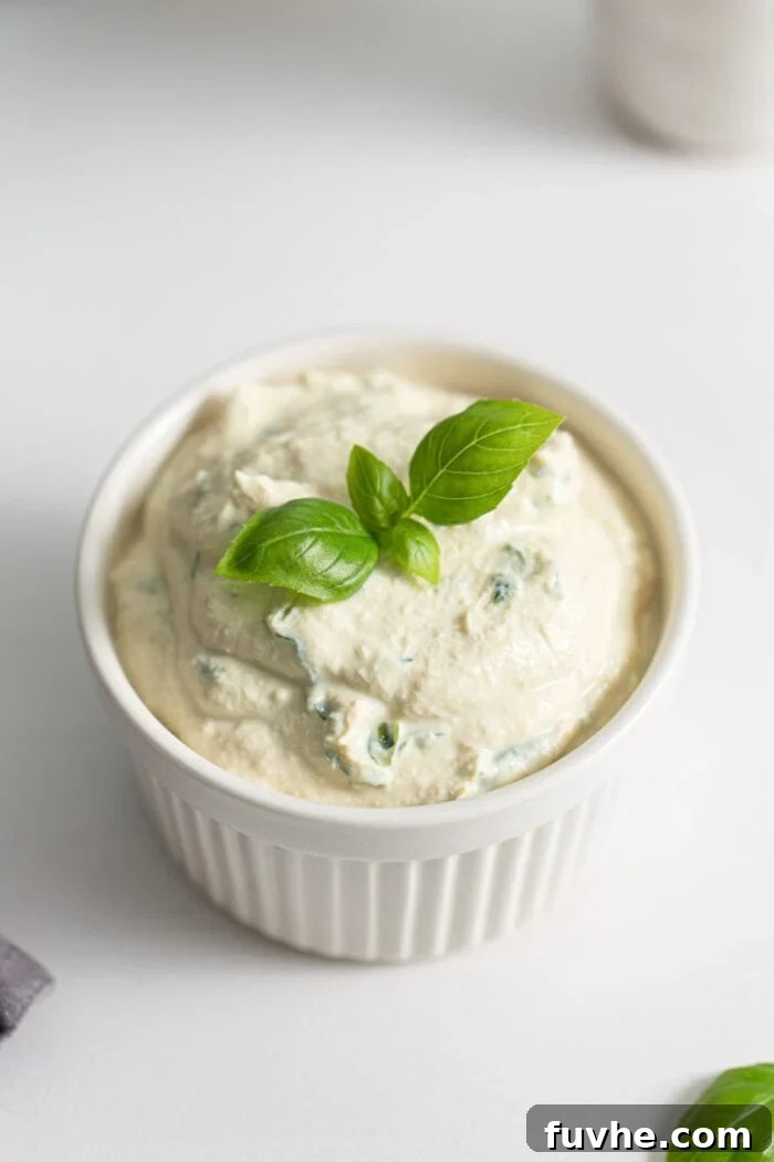 Creamy Vegan Tofu Ricotta 5 Small dish of herb ricotta topped with a piece of fresh basil.