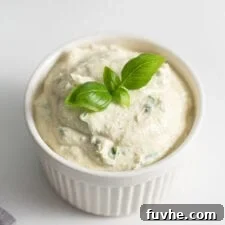 Small dish of herb ricotta topped with a piece of fresh basil.