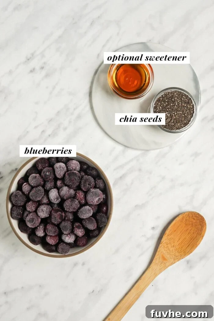 Whip Up Easy Berry Chia Seed Jam in Minutes 3 Blueberries, chia seeds and maple syrup each in a small bowl on a marble surface, ready for jam making.