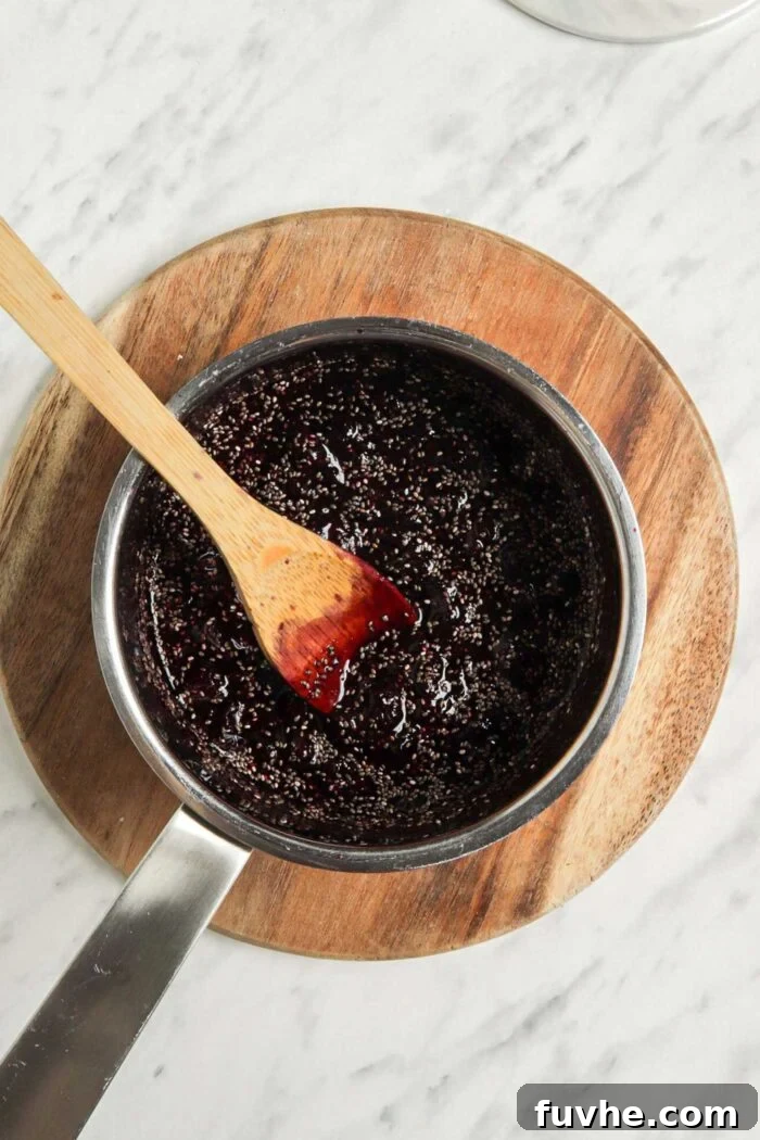 Whip Up Easy Berry Chia Seed Jam in Minutes 5 Mashed blueberries and chia seeds in a saucepan on a cutting board, showing the mixture after adding chia seeds.