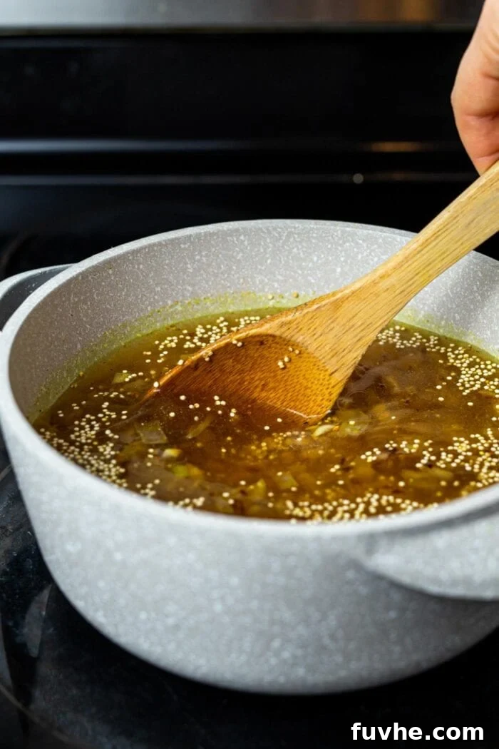A pot of broth with lentils and quinoa simmering on a stovetop.