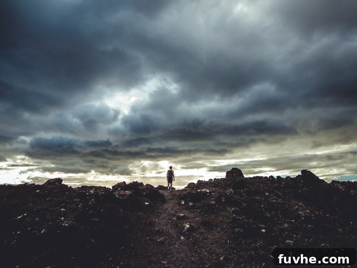 Unforgettable Maui Experiences 15 A man walking on a rocky trail on a stormy day.
