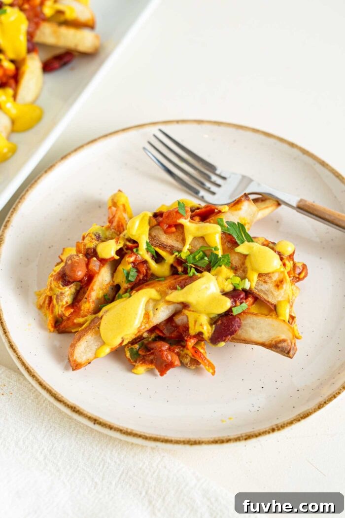 Ultimate Vegan Chili Cheese Fries 2 A small plate of baked potato fries topped with chili and cheese sauce, ready to be enjoyed.