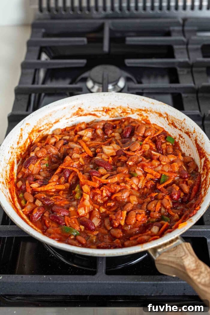 Ultimate Vegan Chili Cheese Fries 6 Cooked chili simmering in a skillet on a gas range stove top, thickening nicely.
