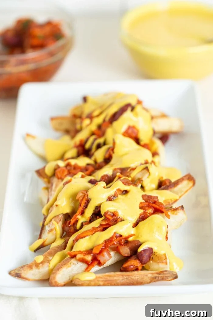 Ultimate Vegan Chili Cheese Fries 9 A plate of baked fries topped with chili and cheese sauce, beautifully arranged.
