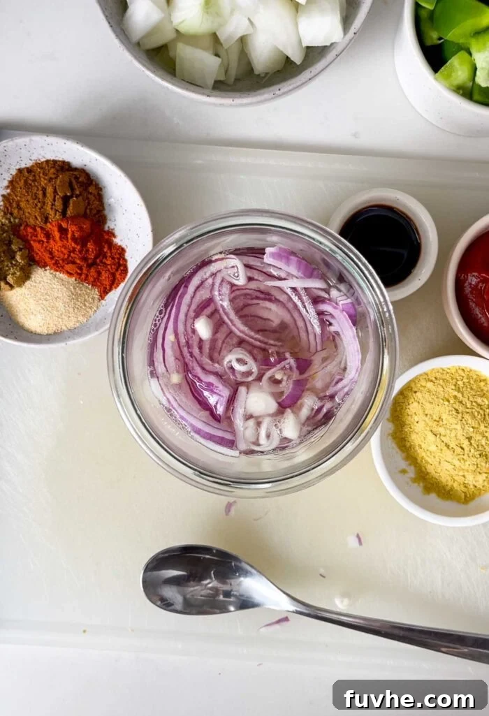 Savory Tempeh Tacos 4 A glass jar filled with thinly sliced red onions soaking in pickling liquid, ready to add a tangy crunch to the tacos.