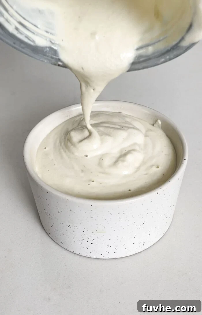 Savory Tempeh Tacos 6 Creamy, zesty cashew sauce being poured from a blender into a small serving dish, ready for drizzling over tacos.