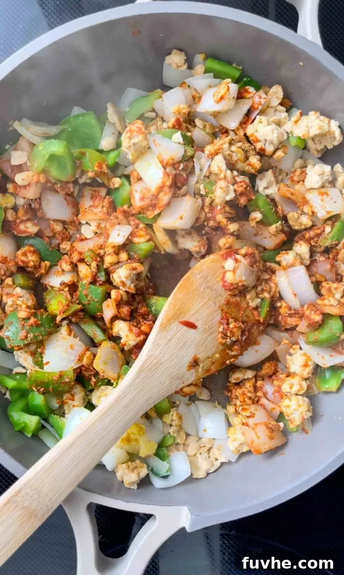 Savory Tempeh Tacos 7 The tempeh, onion, and bell pepper mixture stirred together with rich tomato paste and aromatic spices in a skillet.