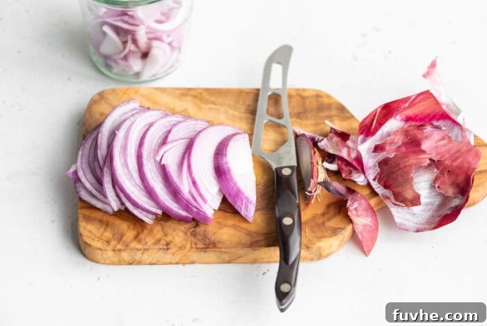 Thinly sliced red onion pieces neatly arranged on a cutting board, ready for pickling.