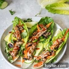 Three tofu lettuce wraps with grated carrot on a plate.