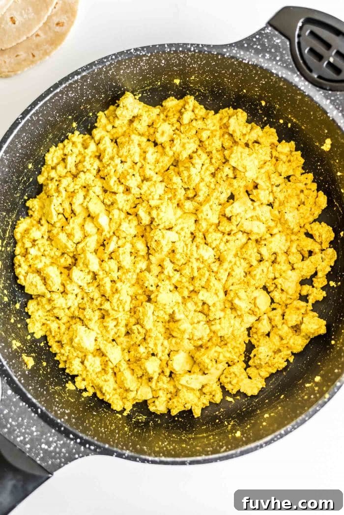 Plant-Powered Breakfast Tacos 4 A close-up shot of perfectly cooked tofu scramble in a black skillet, showcasing its vibrant yellow color and appealing texture.