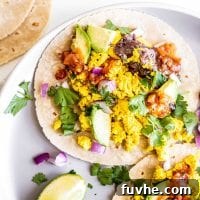 A stuffed vegan breakfast taco on a plate with cilantro, beans and avocado.