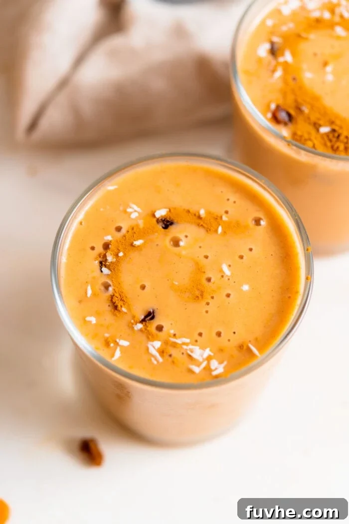 Creamy carrot smoothie in a glass topped with a few raisins and a sprinkle of coconut.