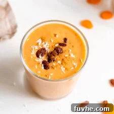 Creamy carrot smoothie in a glass topped with a few raisins.
