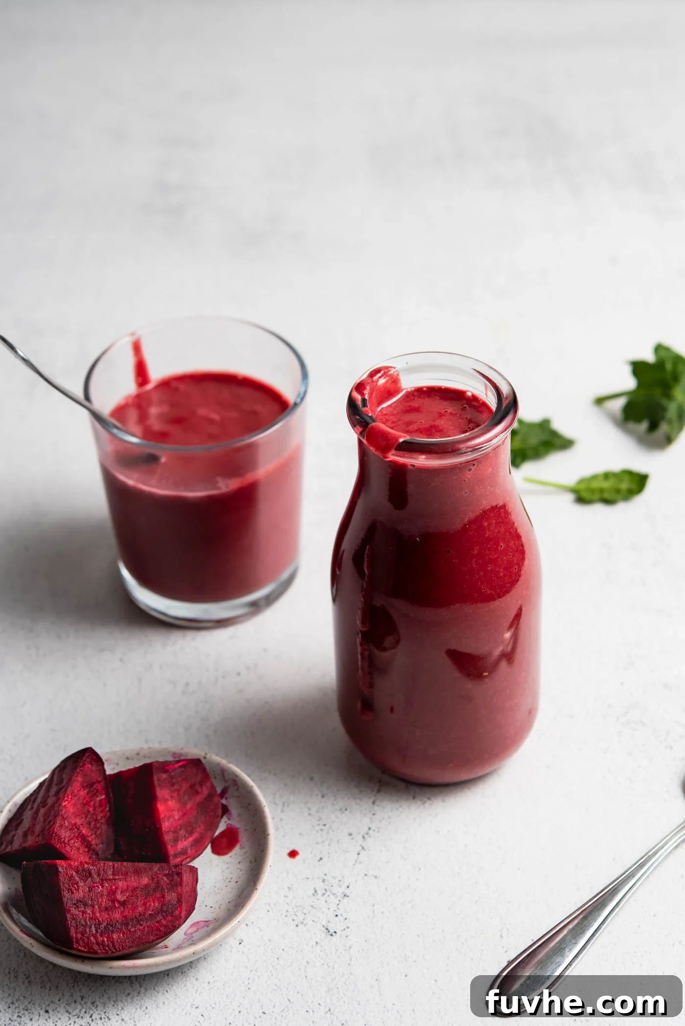 Beet orange protein smoothie in a jar, with a smaller glass and chopped beets nearby.