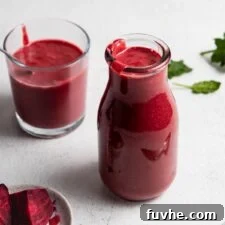 Beet orange protein smoothie in a jar, with a smaller glass and chopped beets nearby.