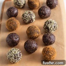 Chocolate energy balls rolled in coconut sugar and hemp seeds on a cutting board lined with parchment paper.