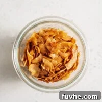 Glass jar of vegan coconut bacon sitting on a white surface.
