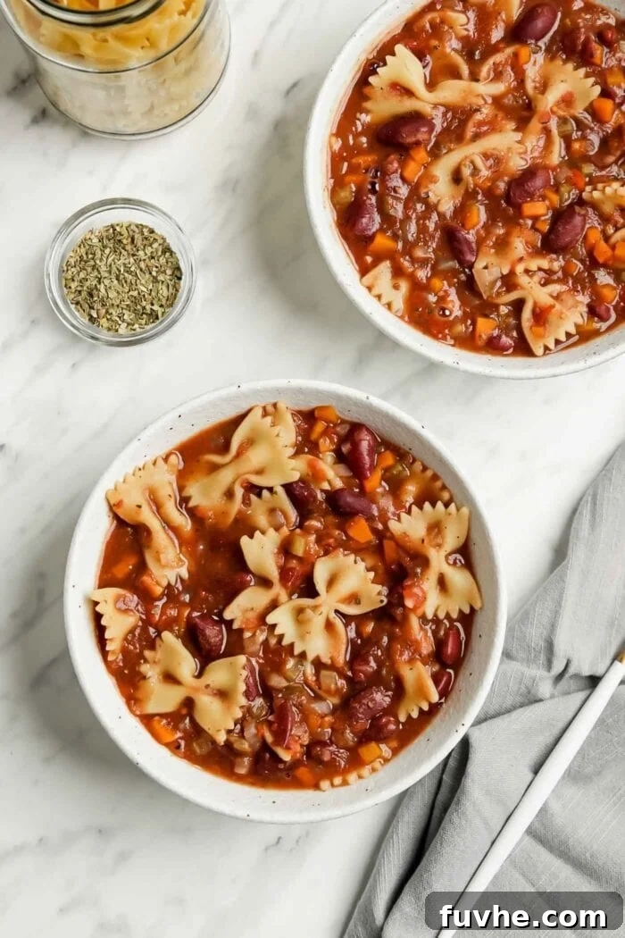 Hearty Plant-Based Minestrone 6 Overhead view of two bowls of minestrone soup with pasta, beans, and fresh greens.