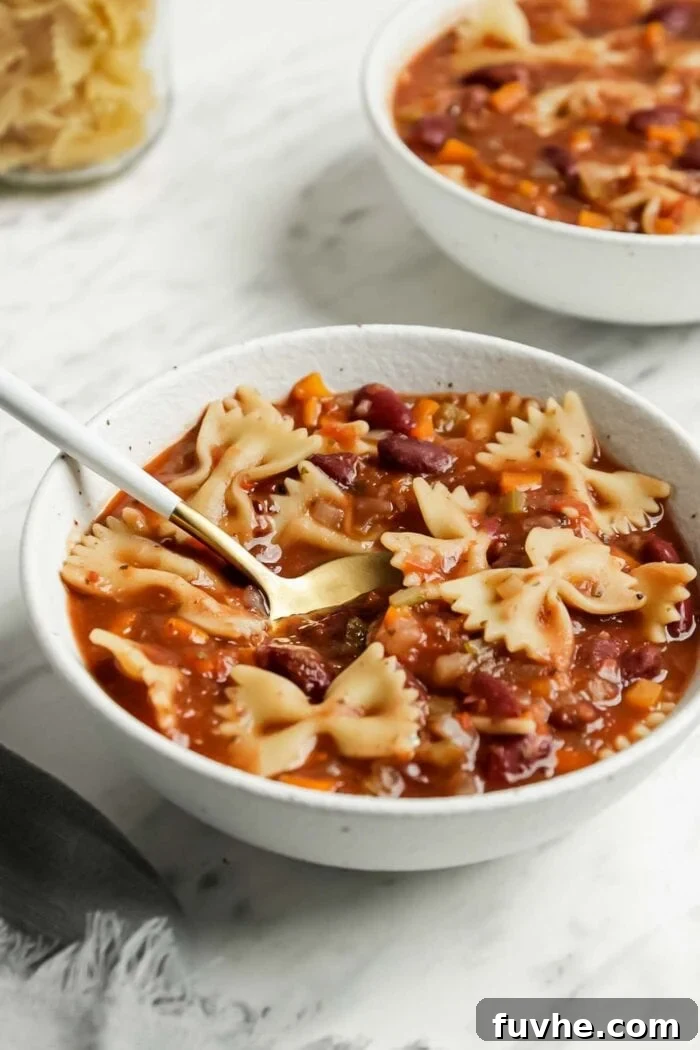 Hearty Plant-Based Minestrone 7 A spoon resting in a bowl of vibrant vegan minestrone soup, ready to be eaten.