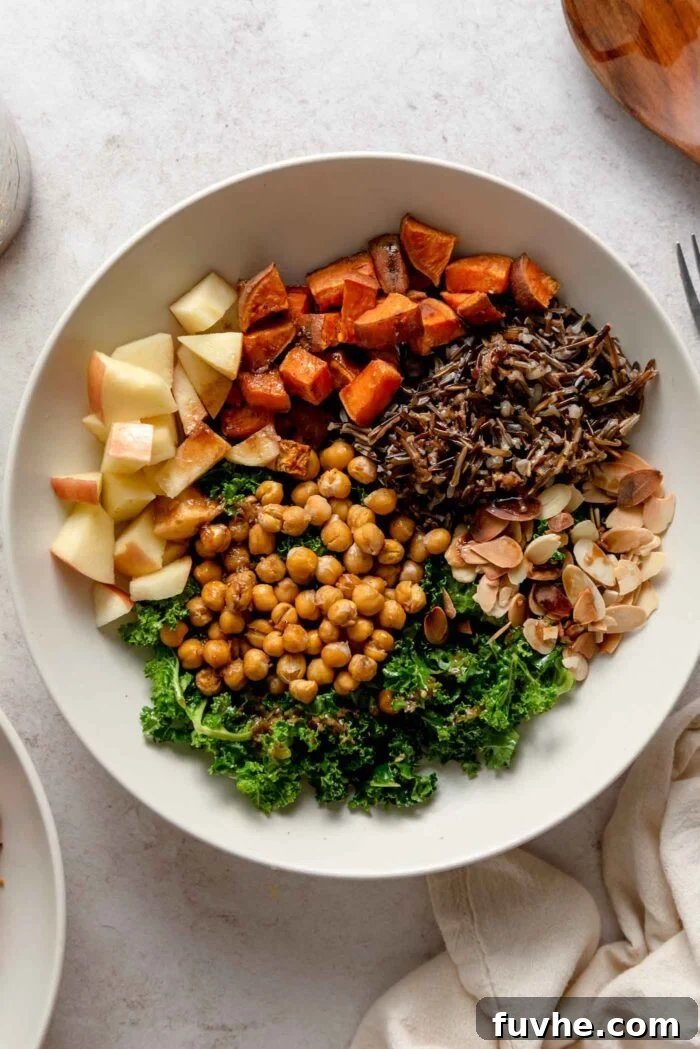 Overhead view of a harvest bowl with kale, chickpeas, apple, almonds and wild rice.