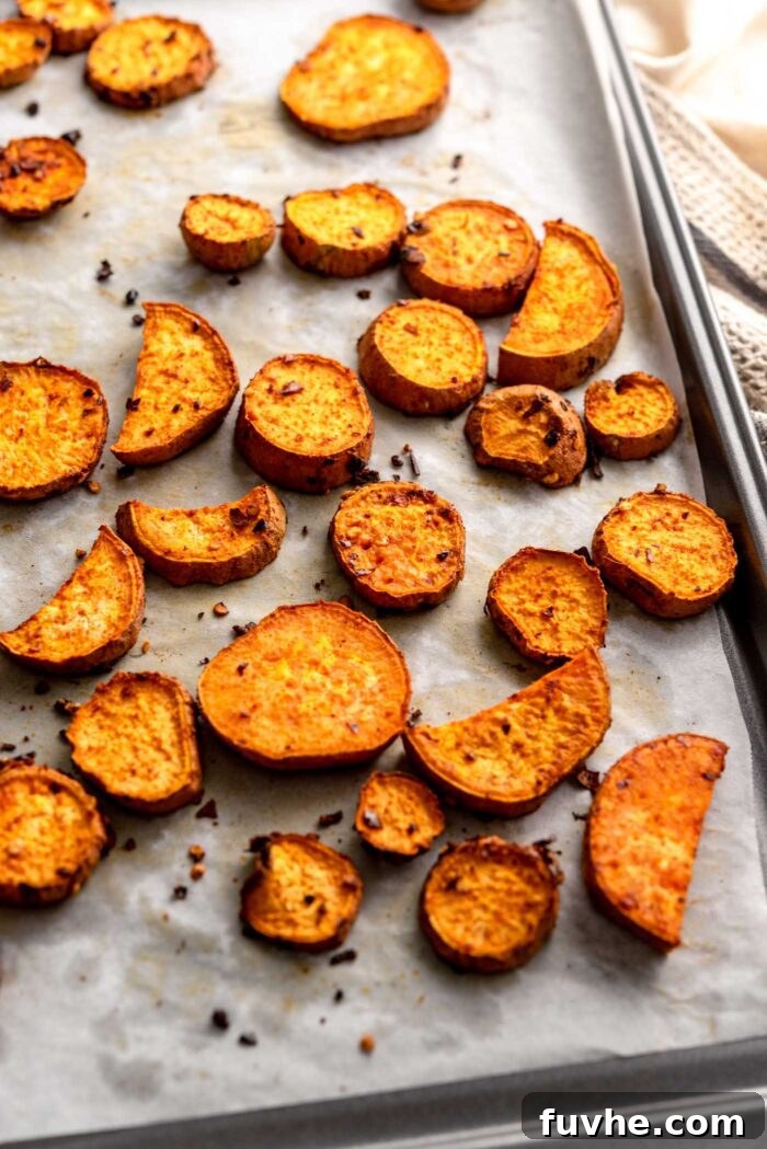 Round slices of baked sweet potato on a baking tray lined with parchment paper.