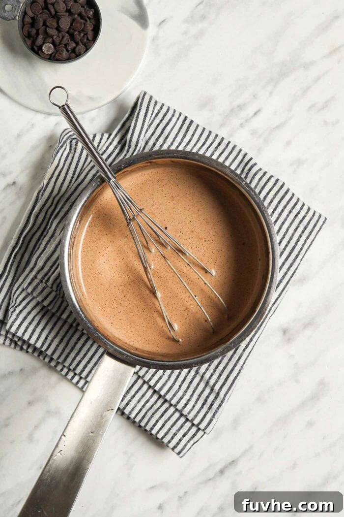 Decadent Plant-Based Hot Chocolate 4 Whisk sitting in a small saucepan of hot chocolate.